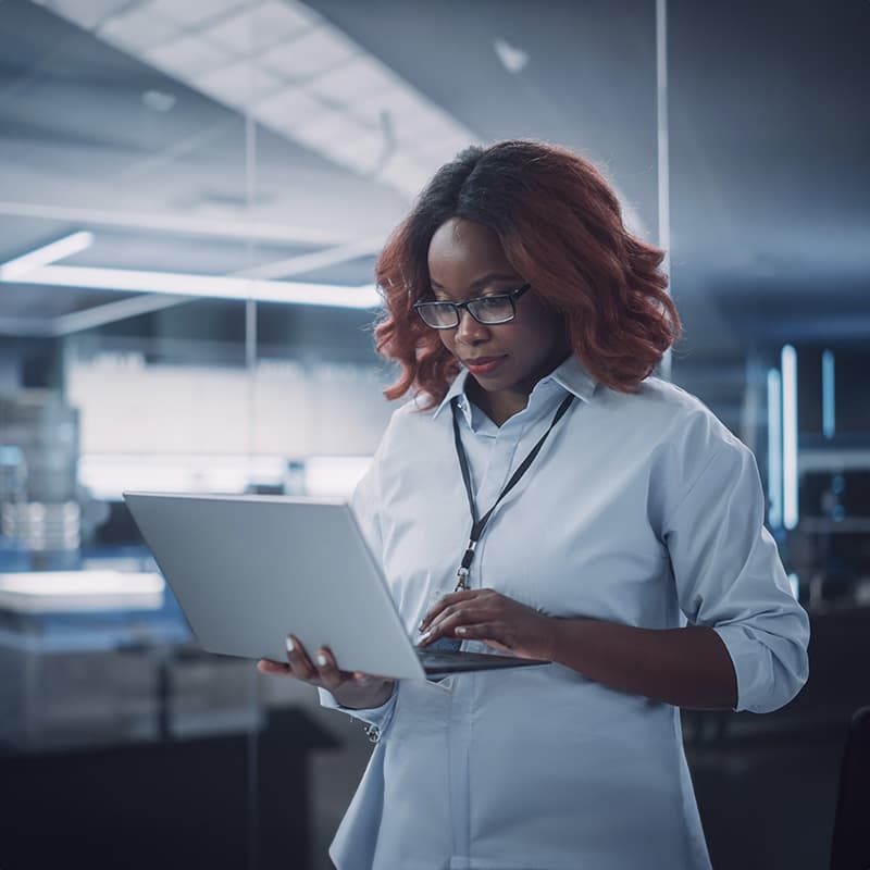 Woman wearing a barge working on laptop in an office space