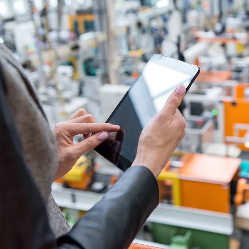 Woman using tablet overlooking a workplace from a balcony