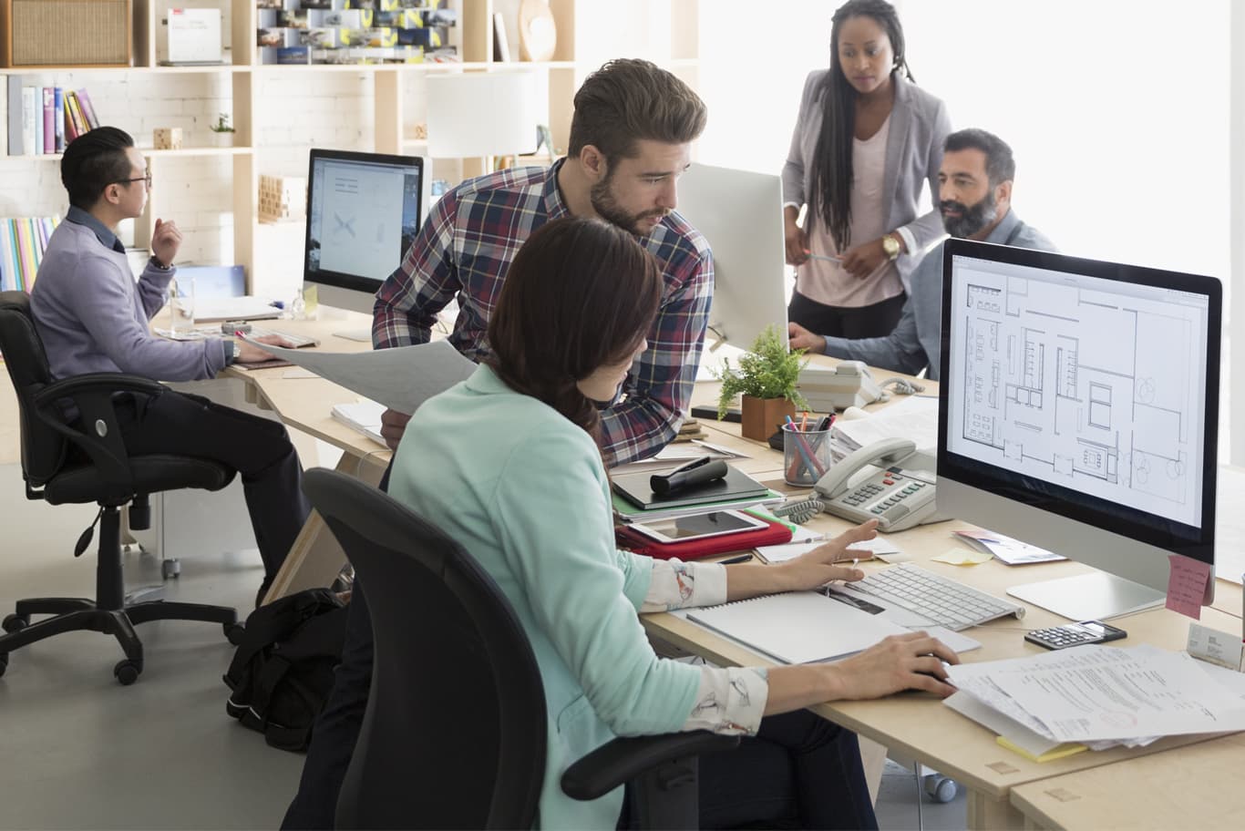 Employees working at computers in open plan office.