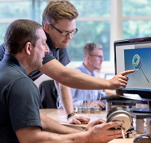 Man holding 3d printed shape showing coworkers