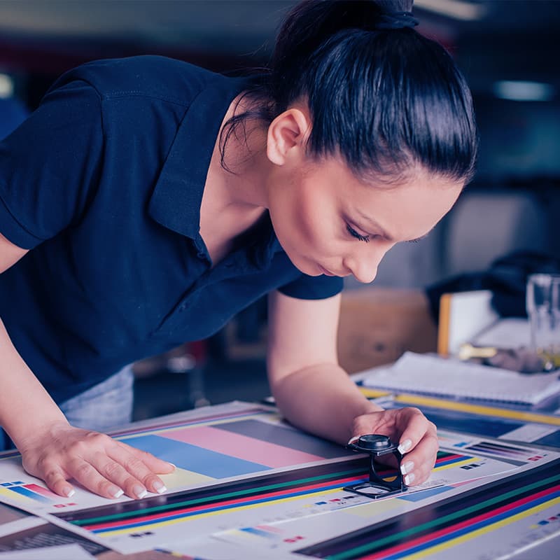 Worker in printing and press centar uses a magnifying glass