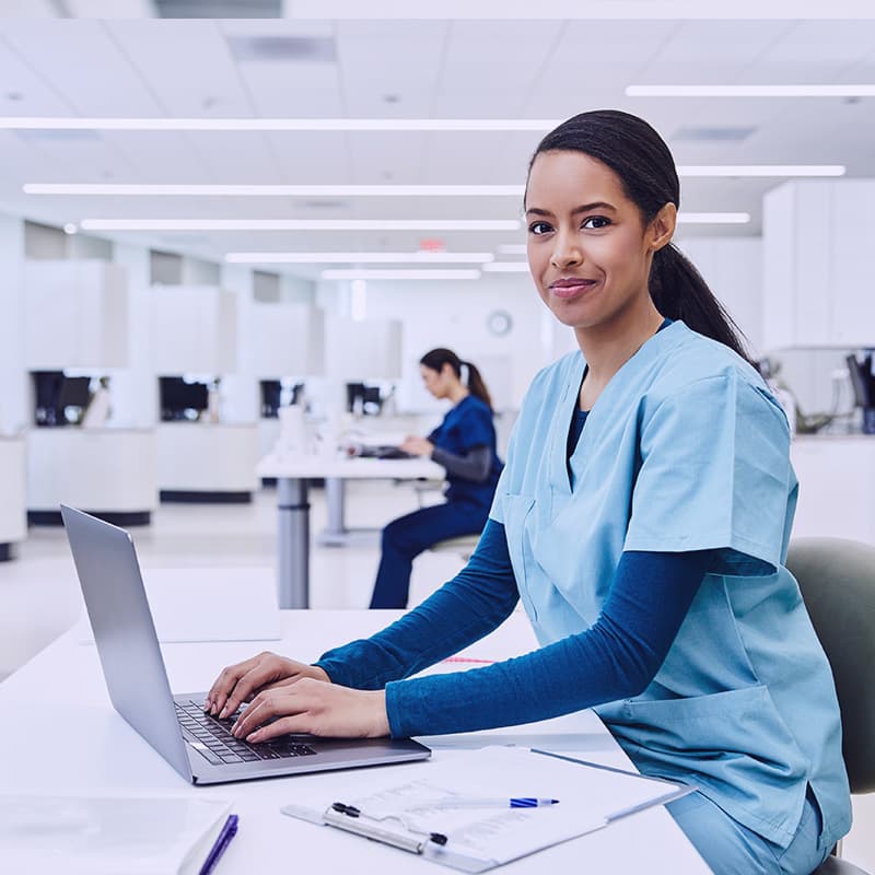 Portrait of confident student using laptop at desk in dental clinic