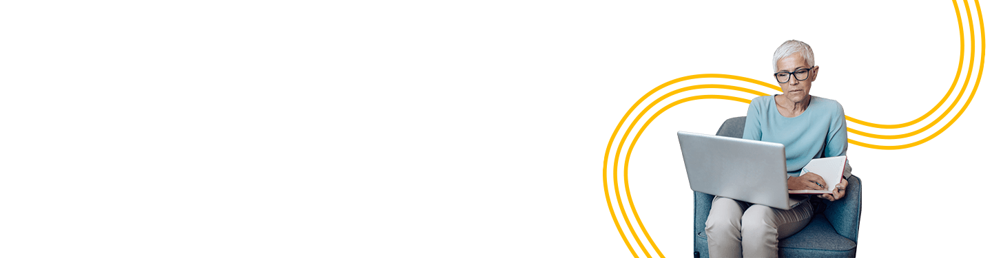 Older woman working on her laptop while sitting in a living room chair