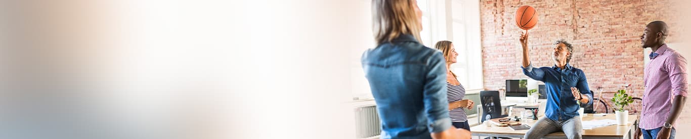 Group of colleagues meeting in a relaxed environment with their work stations in the background