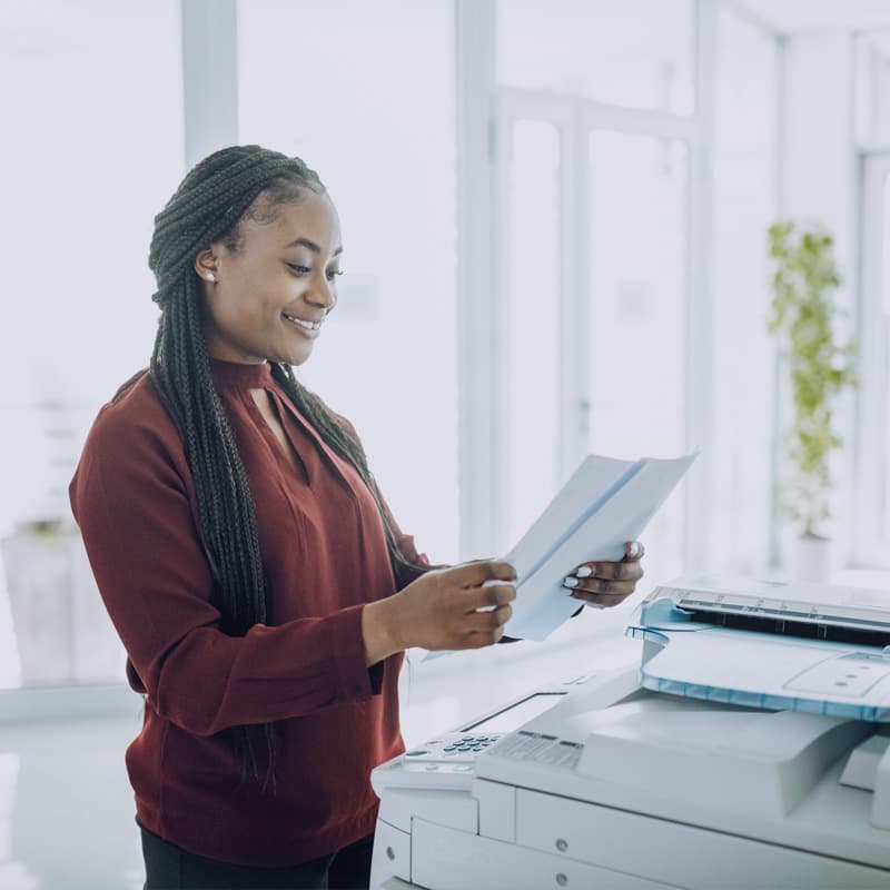 Woman checking recently printed papers, in front of a printer